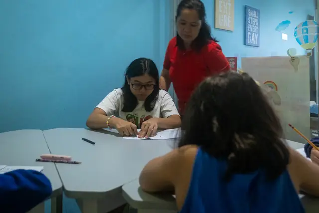 A teacher checking a student's work in a bright classroom